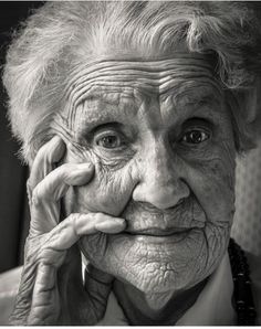 an old woman with wrinkles on her face is holding her hand to her ear