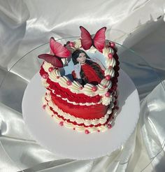 there is a red and white cake on the table with butterflies around it, as well as an image of a woman