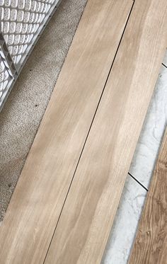 two pieces of wood sitting on top of a floor next to a metal grate