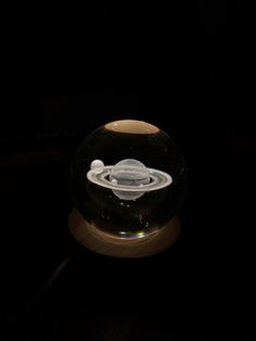 a glass ball with a white object inside it on a wooden base in the dark