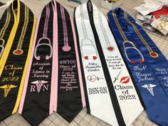 four graduation sashes are lined up on the floor in front of a pile of other ribbons