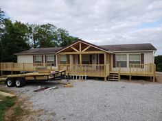 a trailer parked in front of a house with two decks on each side and an attached porch