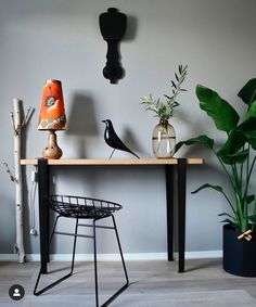 a table that has some plants on it next to a lamp and a bird figurine