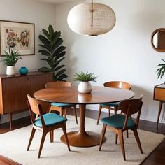 a dining room table surrounded by chairs and potted plants