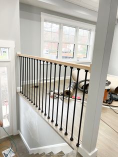 an empty room is being remodeled with wood flooring and black iron handrails