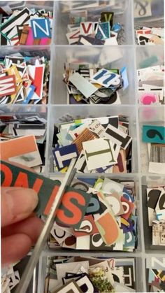 a person is holding scissors in a box full of stickers and letters that spell out the letter s