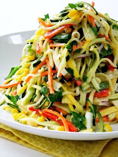 a white plate topped with pasta and veggies on top of a yellow table cloth