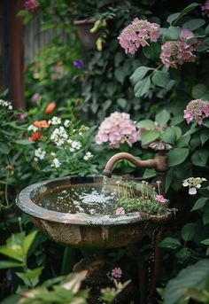 a bird bath surrounded by flowers and greenery