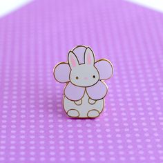 a white and pink elephant pin sitting on top of a purple table next to polka dots