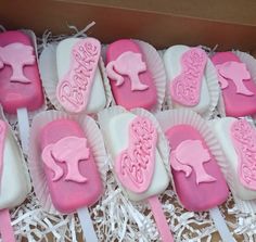 a box filled with pink and white cake pops covered in frosting next to each other