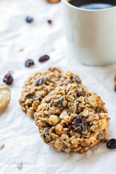 an oatmeal cookie with raisins and cranberries next to a cup of coffee