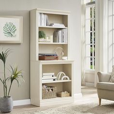 a living room with a couch, chair and bookshelf on the floor in front of a window