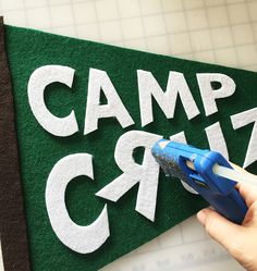 someone is cutting out the word camp crazy on a green felt board with scissors and glue