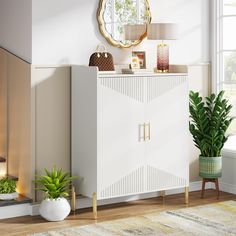 a white cabinet sitting next to a potted plant and a mirror on the wall