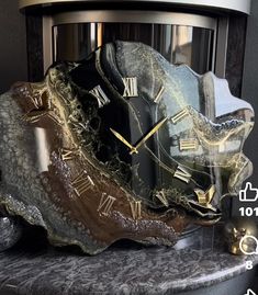 a clock that is sitting on top of a marble block with gold and black accents