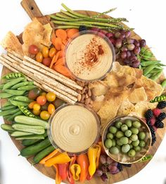 a platter with dips, crackers, vegetables and fruit arranged in the shape of a circle