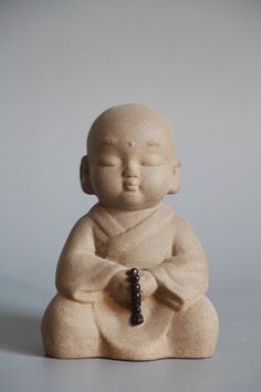 a small buddha statue sitting on top of a white table next to a black beaded necklace