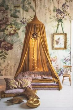 a canopy bed sitting in the middle of a living room next to a wall with flowers on it