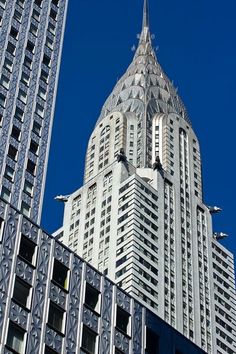 the top of a tall building in front of other buildings on a clear blue sky day