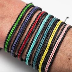 a person's arm with several different colored bracelets on top of each other