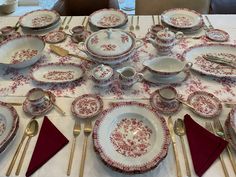 the table is set with red and white china plates, silverware, and napkins