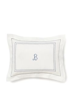 a white pillow with blue embroidered monogrammed on the front and bottom, sitting against a