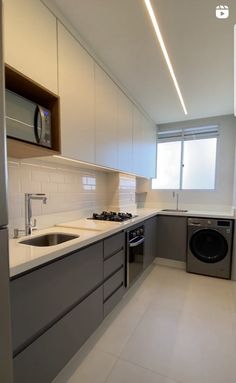 an empty kitchen with stainless steel appliances and white counter tops, including a washer and dryer