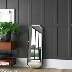 a mirror sitting on top of a wooden dresser next to a potted green plant