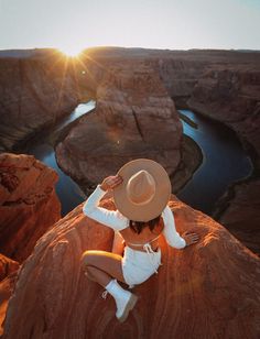 a woman sitting on top of a large rock next to a river in the desert