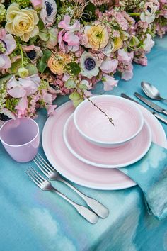 the table is set with pink plates and silverware