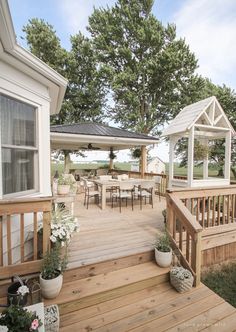 a wooden deck with potted plants on it and a gazebo in the background