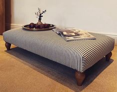 a tray with some fruit on top of a striped footstool in front of a white wall