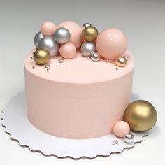 there is a pink cake with gold and silver decorations on the top, along with two balls