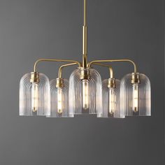 a brass chandelier with five clear glass shades