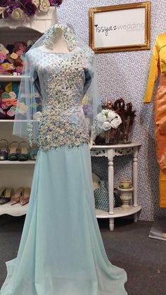 a dress on display in a store with mannequins and other items behind it