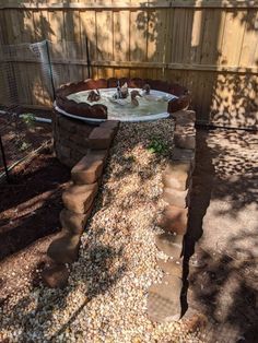 an outdoor hot tub in the middle of a yard with rocks and gravel around it