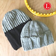 two knitted hats sitting on top of a wooden table next to a yellow hoop