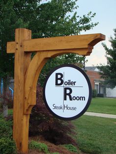 a sign for boiler room in front of a tree and grass area with bushes around it