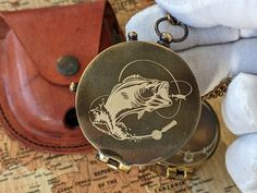 a pocket watch sitting on top of a map next to a leather case and chain