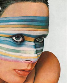 a woman's face painted with multicolored stripes on her skin and eyes