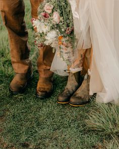 two people standing next to each other wearing boots and holding bouquets in their hands