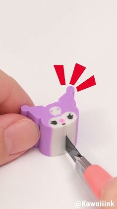 someone is cutting out the shape of a small toy with scissors and glue on it