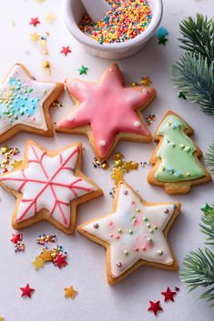 decorated christmas cookies with sprinkles next to a cup of coffee and fir tree