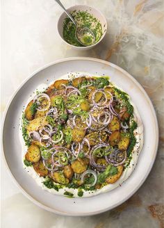 a white plate topped with broccoli and onions next to a bowl of pesto