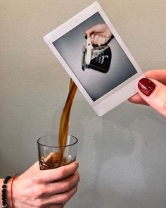 a woman is pouring coffee into a glass while another person holds up a polaroid