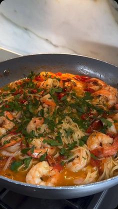 a skillet with shrimp and noodles on the stove