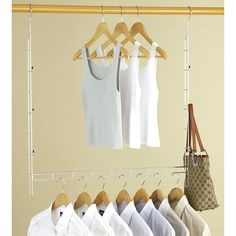 there are many white shirts hanging on the clothes rack in front of a beige wall