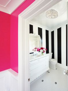 a bathroom with black and white stripes on the walls, pink flowers in vases