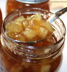 a glass jar filled with pickled apples on top of a white tablecloth next to jars