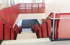 the stairs are red and black in this modern building with metal railings on both sides